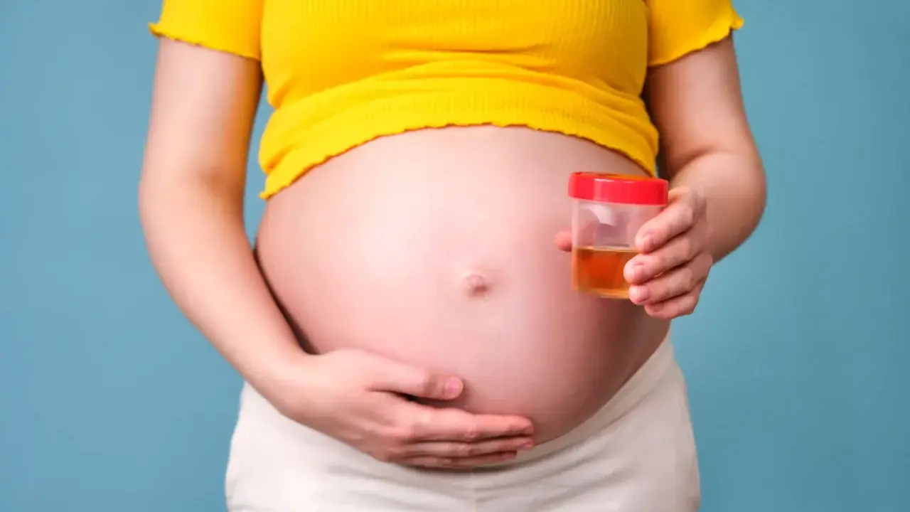 Ciężarna kobieta trzyma pojemnik z próbką moczu, badanie na obecność ketonów w moczu w ciąży.