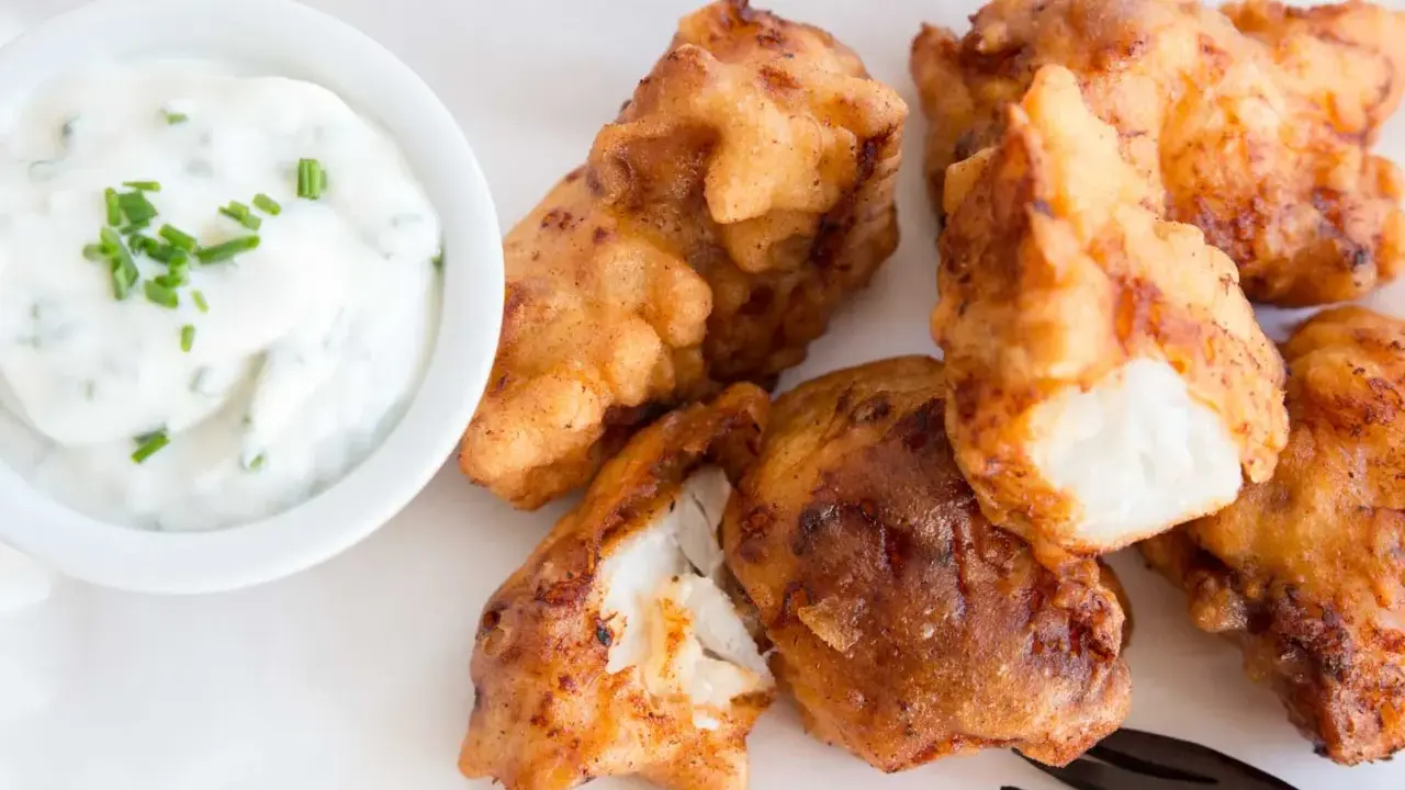 Knusprig frittierte Fischstücke, perfekt für ein Kibbeling Rezept, mit einem cremigen Dip mit Schnittlauch.