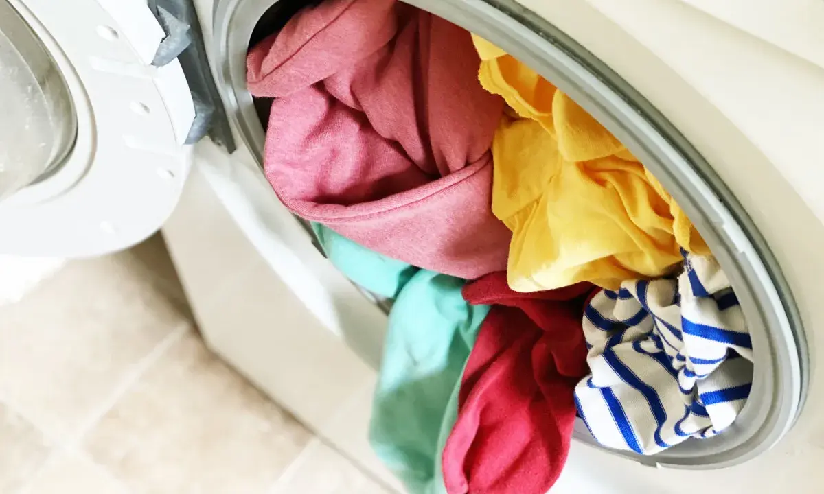 Carga de lavadora con ropa de colores variados, incluyendo rosa, amarillo, turquesa y rayas azules. ¡A ver si se puede lavar ropa blanca con ropa de color sin problemas!