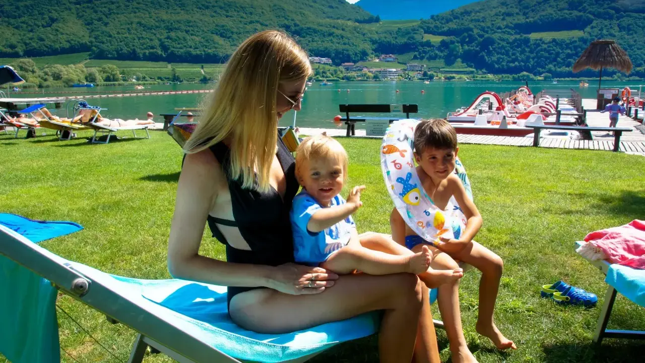 Rodzina odpoczywa nad jeziorem Lago di Caldaro. Słońce, zieleń i woda tworzą idealne wakacje.