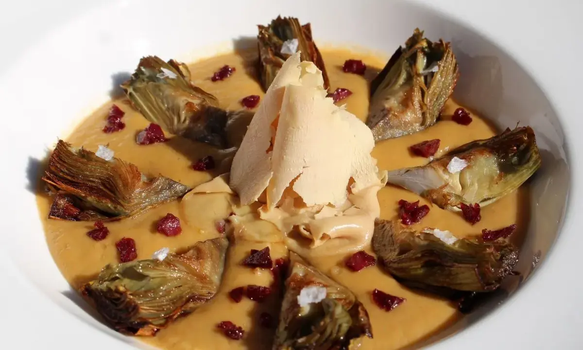 Delicioso guiso de alcachofas con trocitos de jamón y una lámina crujiente de queso.