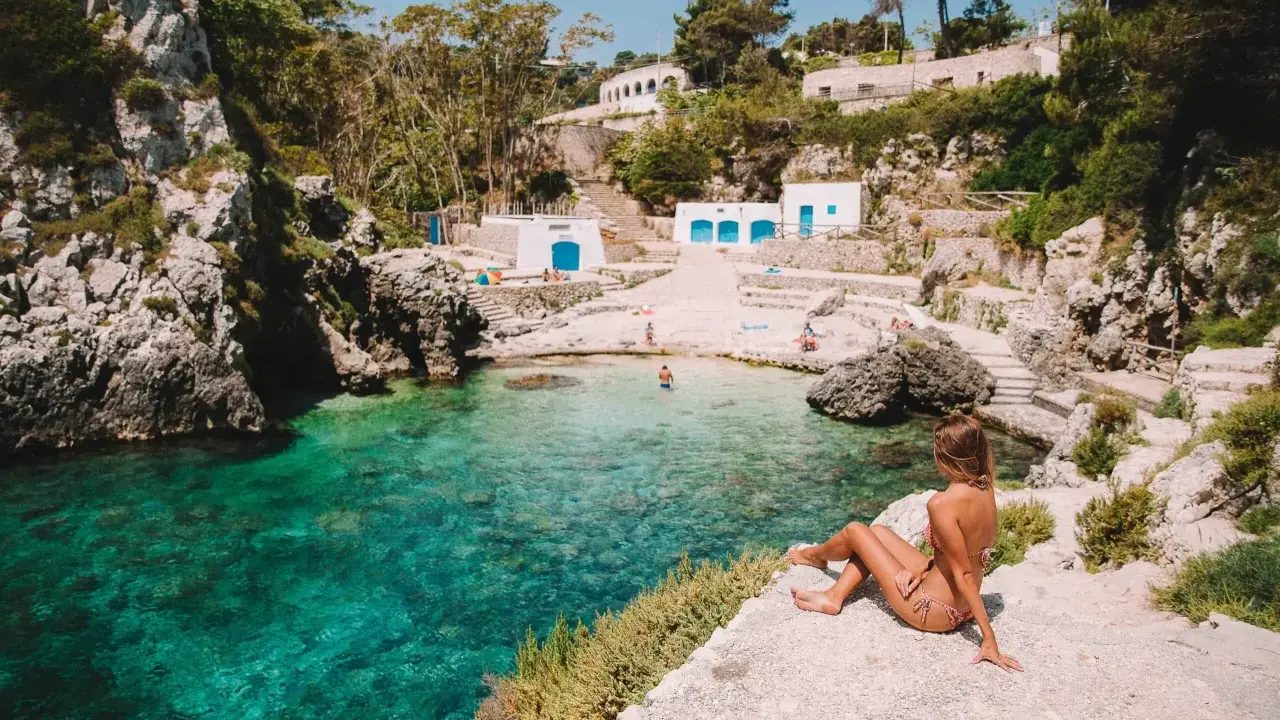 Una donna ammira il mare cristallino di una caletta pugliese. Perfetto per capire quando andare in Puglia per una vacanza indimenticabile.