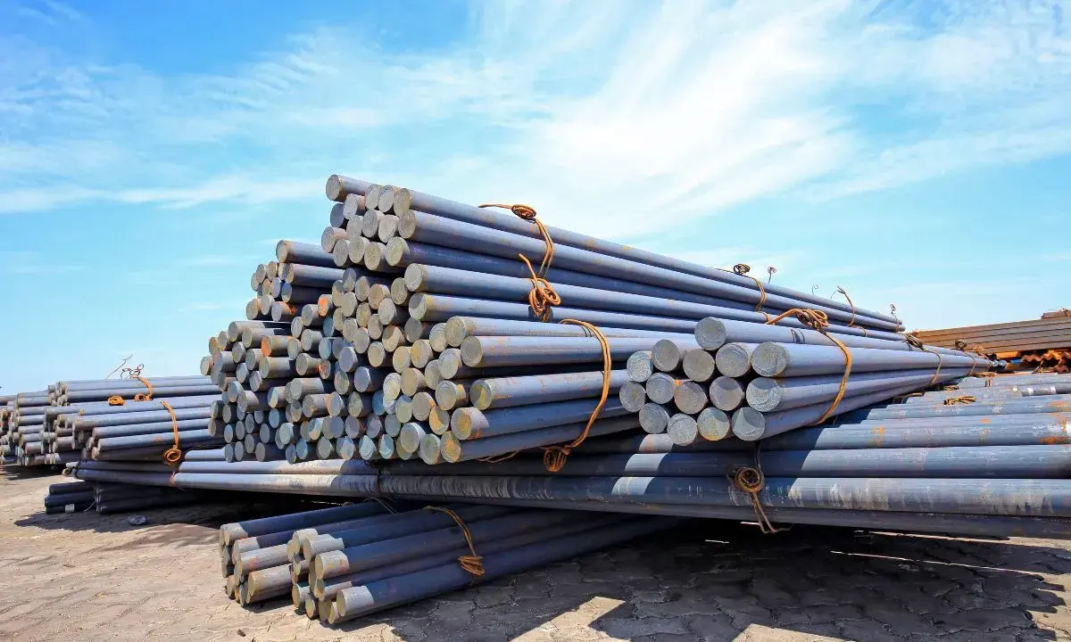 Stapel von Metallstäben, die den Unterschied zwischen Eisen und Stahl veranschaulichen. Sie liegen unter blauem Himmel.