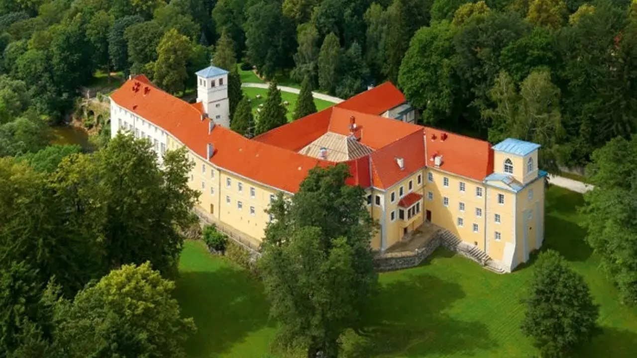 Malowniczy hotel zamek otoczony zielenią.
