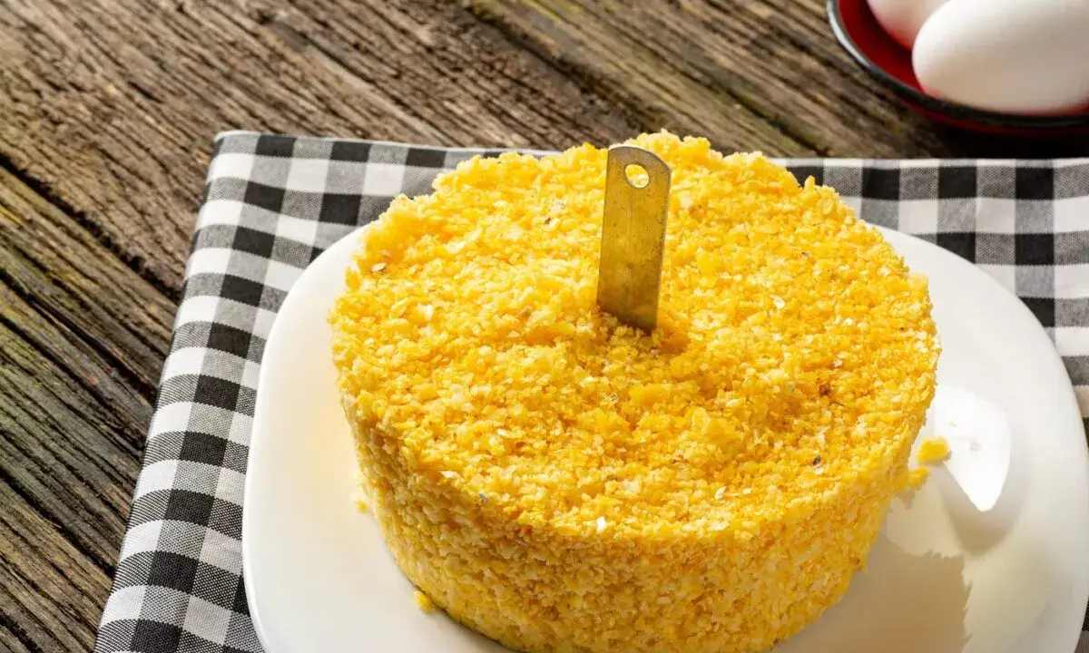 Un pastel de maíz amarillo con un cuchillo insertado, listo para servir. Una guía visual para como hacer cous cous.