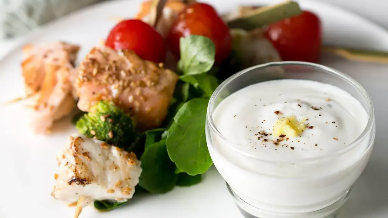 Brochettes de poisson et saumon grillés avec tomates cerises, brocolis et une sauce au yaourt crémeuse.