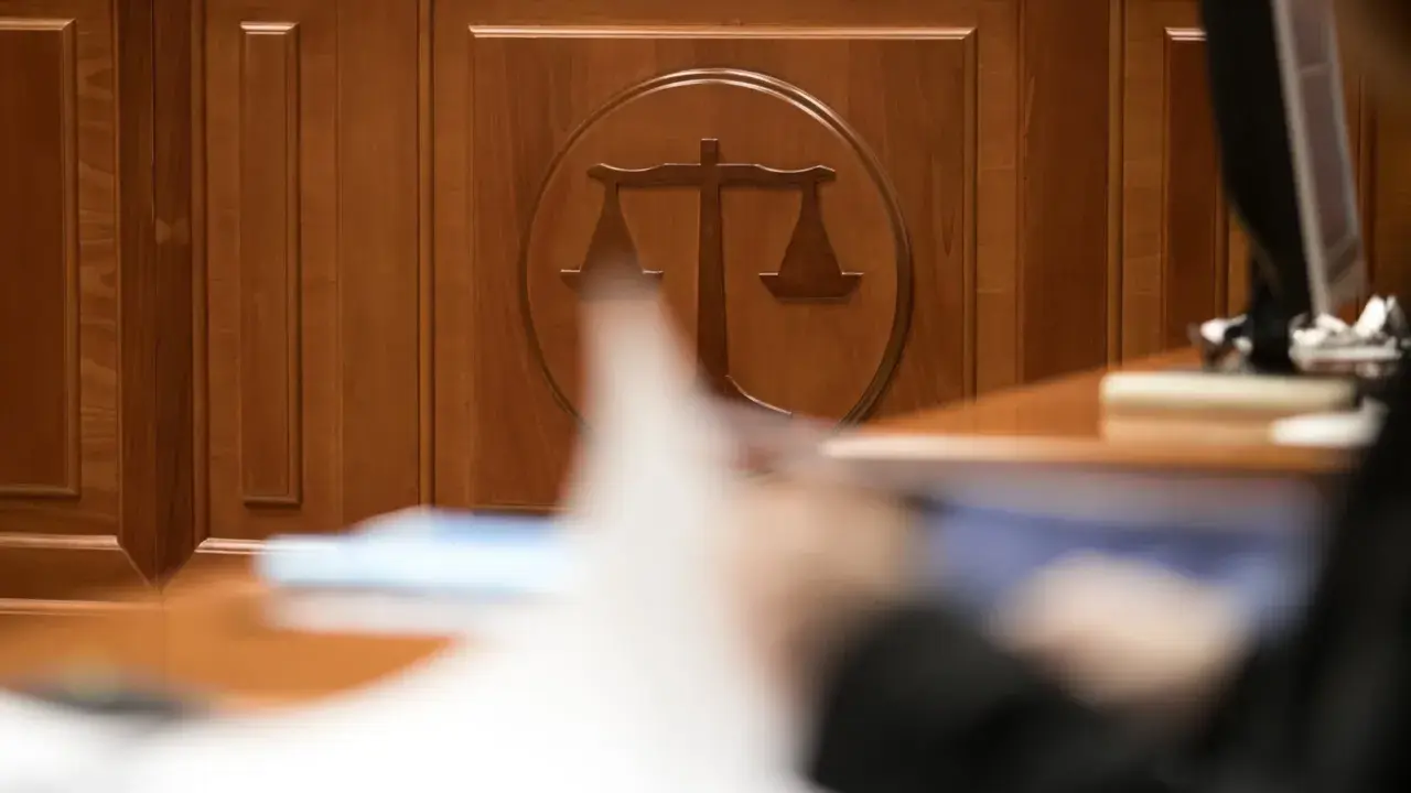 Drewniana ściana z symbolem wagi sprawiedliwości. Zastanawiasz się, ile czeka się na rozprawę w sądzie cywilnym? Czas oczekiwania bywa długi.