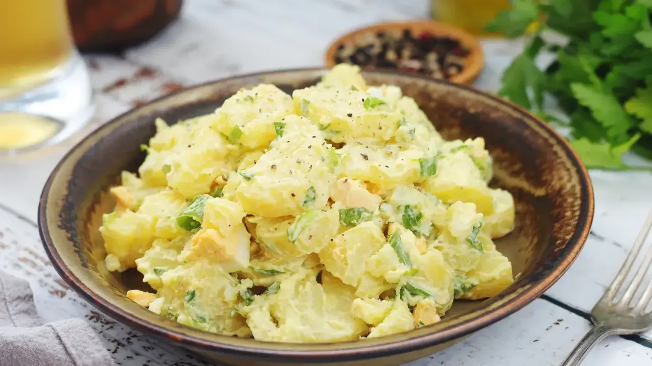 Salade de pomme de terre crémeuse avec des morceaux d'œufs durs et de ciboule, assaisonnée de poivre noir. Un plat réconfortant et savoureux.