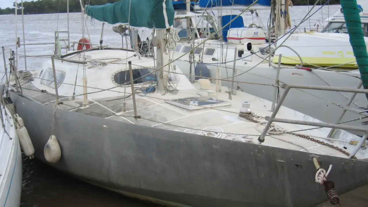 Voilier gris amarré, prêt pour une brise de mer 31. Voiles vertes et bleues, cordages et bouées.