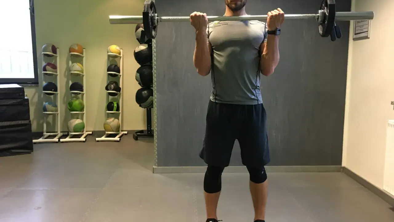 Mann macht Langhantel Curls im Fitnessstudio. Er trainiert seine Bizeps.