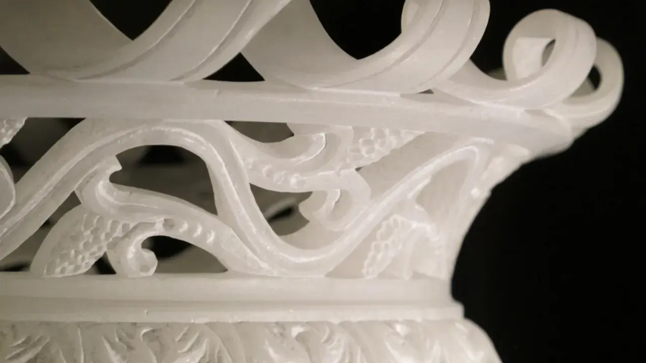 Dettaglio di un vaso in alabastro di Volterra, con decorazioni floreali intagliate e un bordo a onda.
