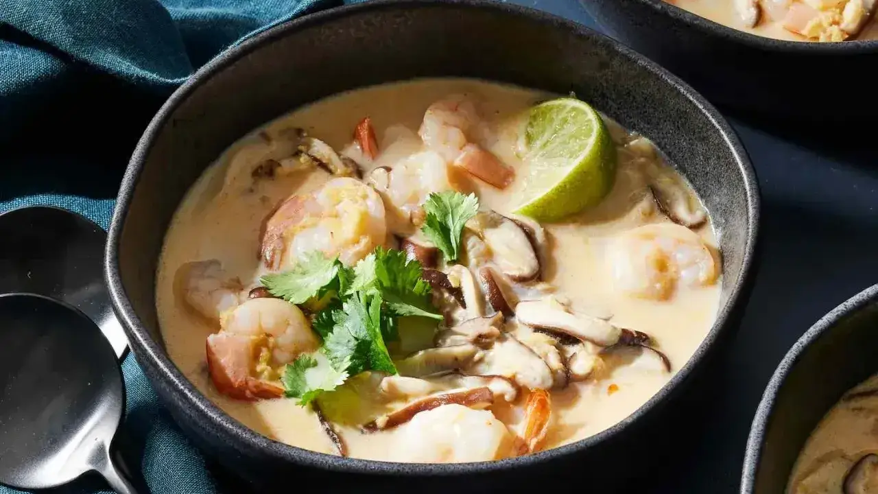 En skål med krämig tom kha gai med räkor, svamp och lime. En smakrik thailändsk soppa.