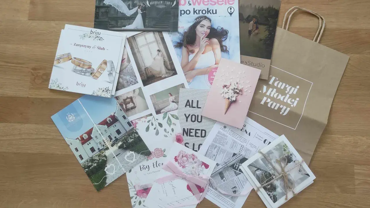 Materiały z targów ślubnych: magazyny, zaproszenia, zdjęcia i torba z napisem "Targi Młodej Pary".
