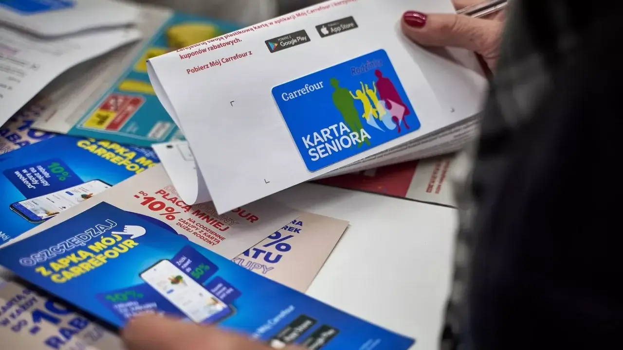 Karta Seniora Carrefour daje zniżki i rabaty. Na zdjęciu widać ulotki i kartę z logo Carrefour.