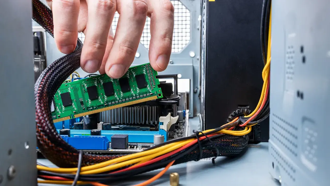 Main d'un homme insérant une barrette de RAM verte dans un emplacement de carte mère. Guide pour comment installer RAM.