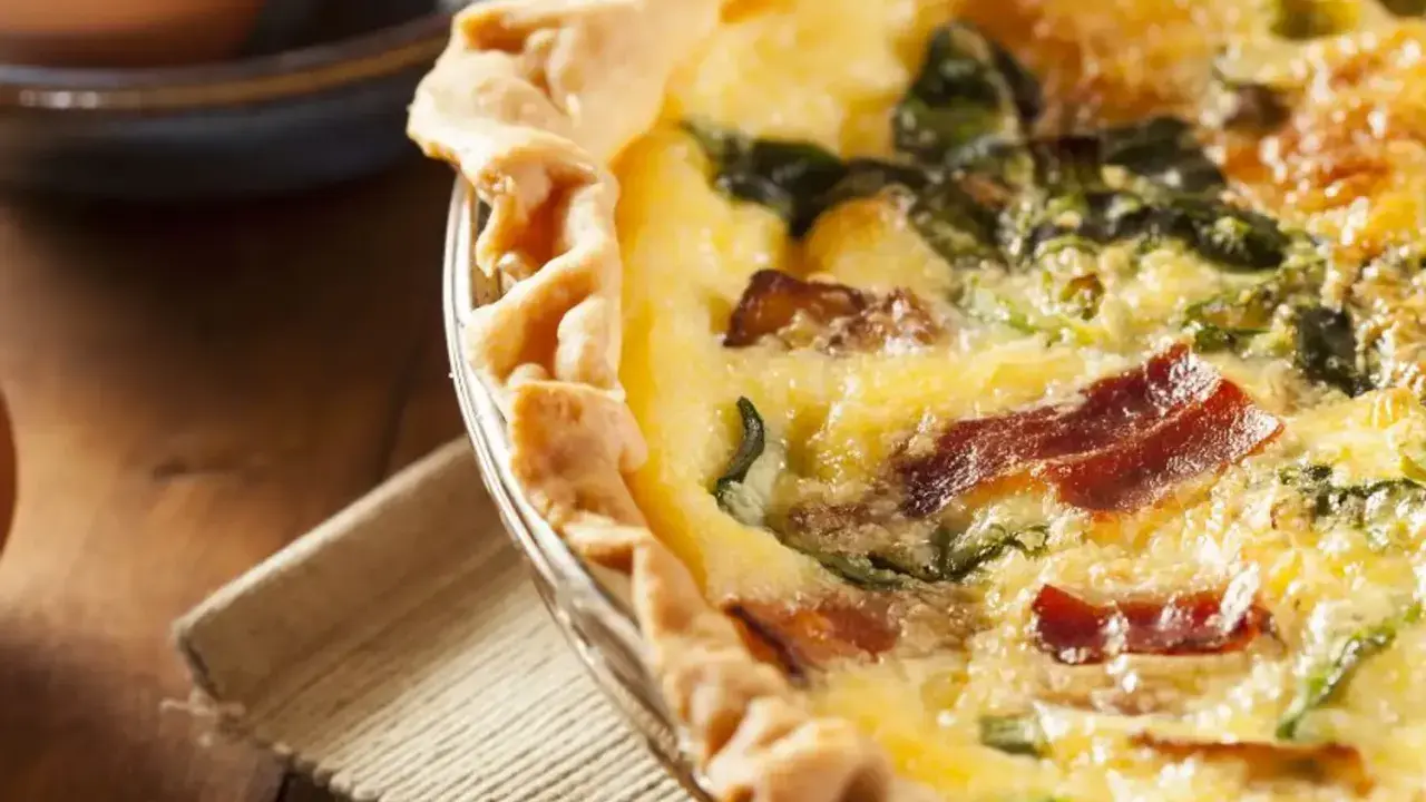 Une délicieuse tarte aux épinards et lardons, dorée et appétissante, prête à être dégustée.