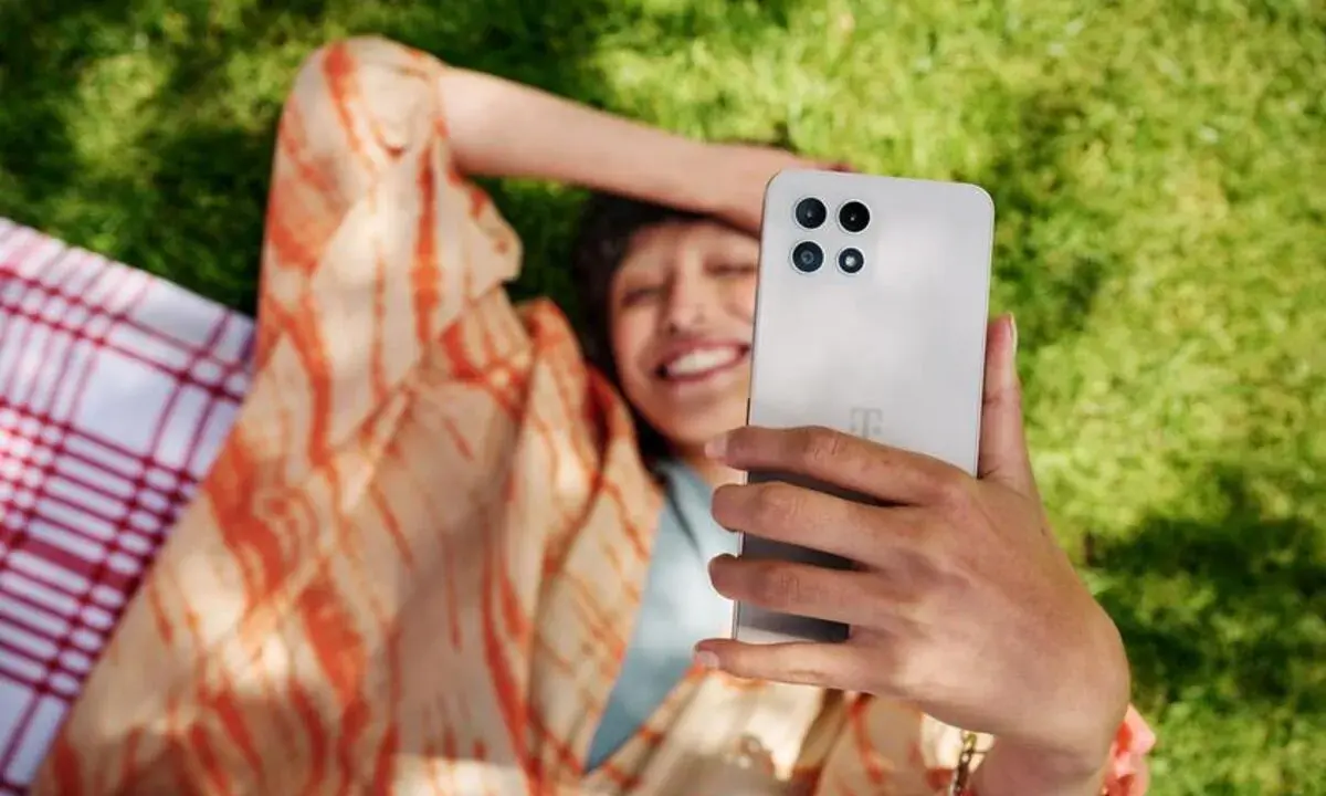 Uśmiechnięta osoba robi selfie na trawie, ciesząc się czasem przed ekranem.