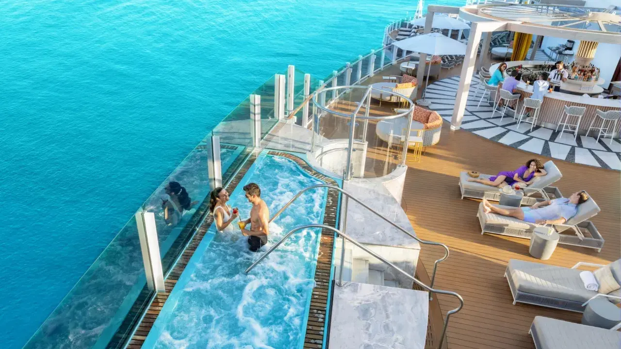 Coppia in jacuzzi su nave da crociera Caraibi, con bar e lettini prendisole. Un sogno di volo e crociera Caraibi.