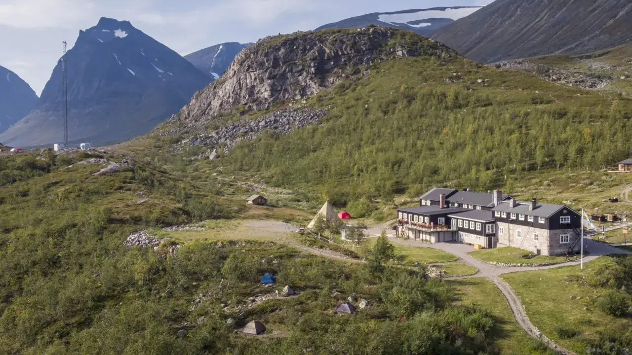 STF Kebnekaise fjällstation med tält och fjäll i bakgrunden. En plats för äventyr och naturupplevelser.