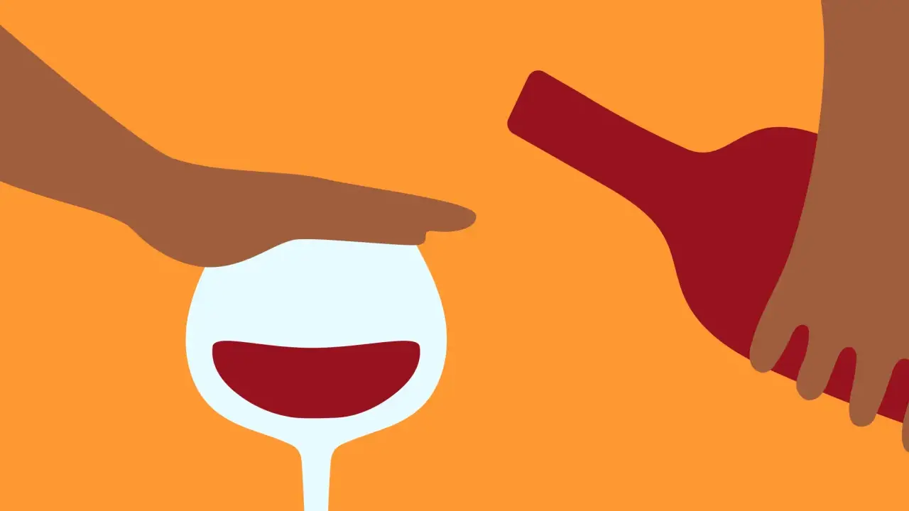 En hand stoppar ett glas rött vin medan en flaska hälls. Kanske en påminnelse om att vara försiktig med alkohol, särskilt om man tar medicin som Diamox.