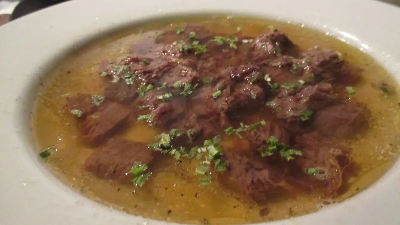 Ein Teller mit Tafelspitz, zartes Rindfleisch in Brühe, garniert mit frischen Kräutern. Ein Klassiker des Tafelspitz Rezepts.