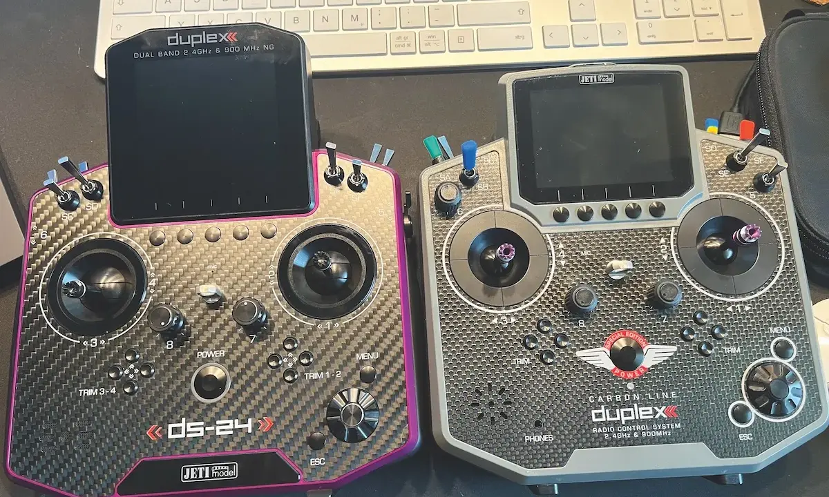 Zwei Jeti DS-24 V2 Fernsteuerungen, eine in Carbon-Optik mit pinkem Rand, die andere in grau. Beide mit Displays und Joysticks.