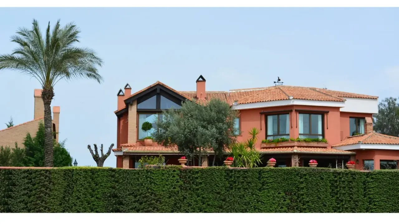 Vistas de casas de lujo en Granada, con palmeras, olivos y un seto verde.