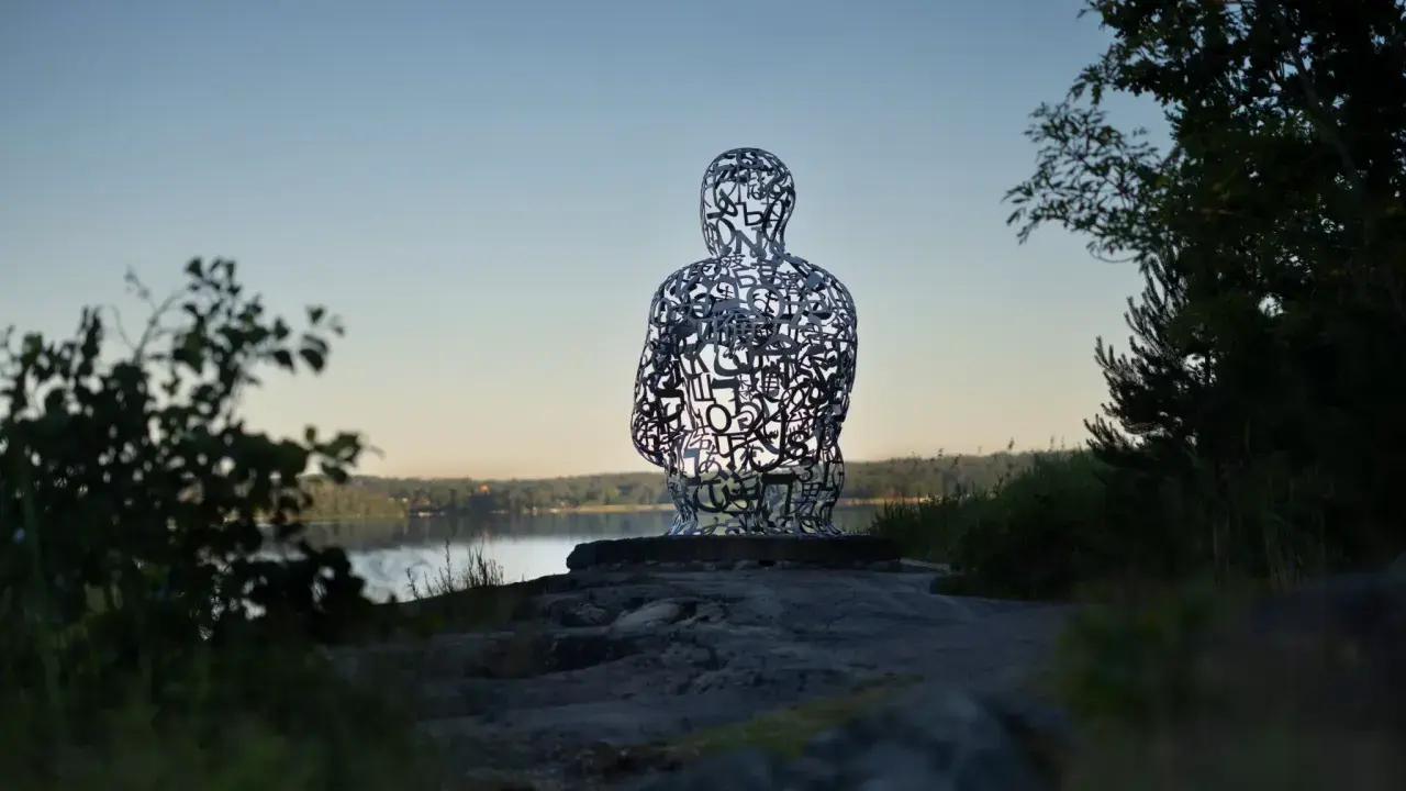 Skulptur av bokstäver vid Artipelag Stockholm, med en sjö i bakgrunden.
