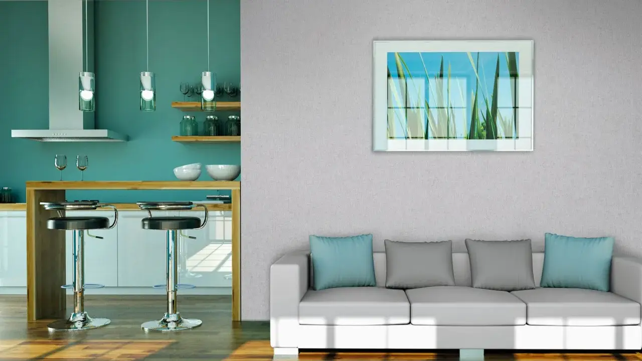 Modernes Wohnzimmer mit Vliestapete tapezieren. Ein weißes Sofa mit blauen und grauen Kissen steht vor einer Wand mit einem Bild von Gräsern. Daneben eine Küche mit Bar.