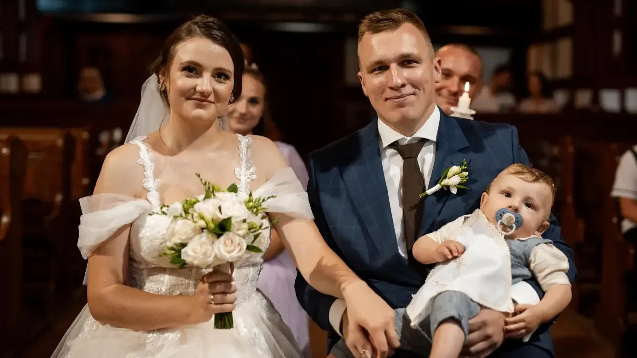 Para młoda z dzieckiem na rękach, podwójna uroczystość: ślub i chrzest w jednym.