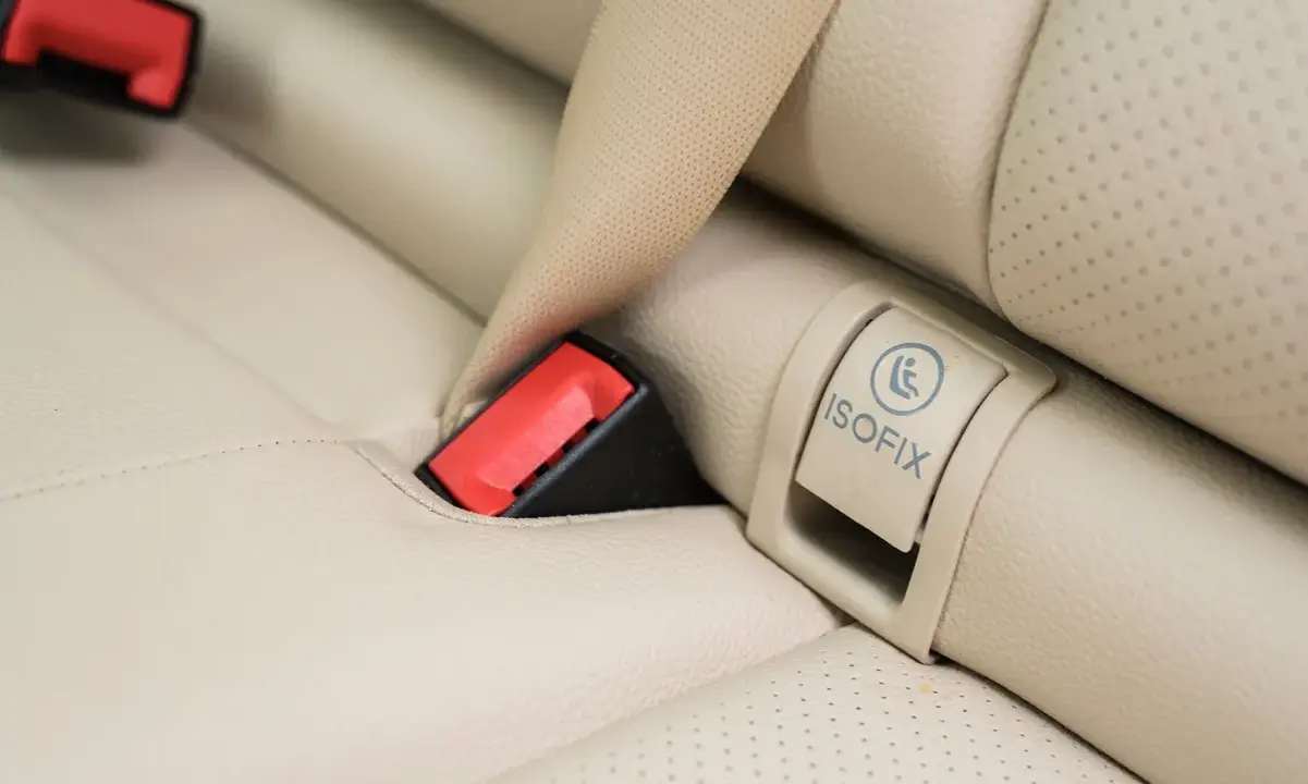 Zapięcie pasa bezpieczeństwa i oznaczenie ISOFIX na jasnej, skórzanej kanapie samochodowej. Czy baza isofix pasuje do każdego fotelika?