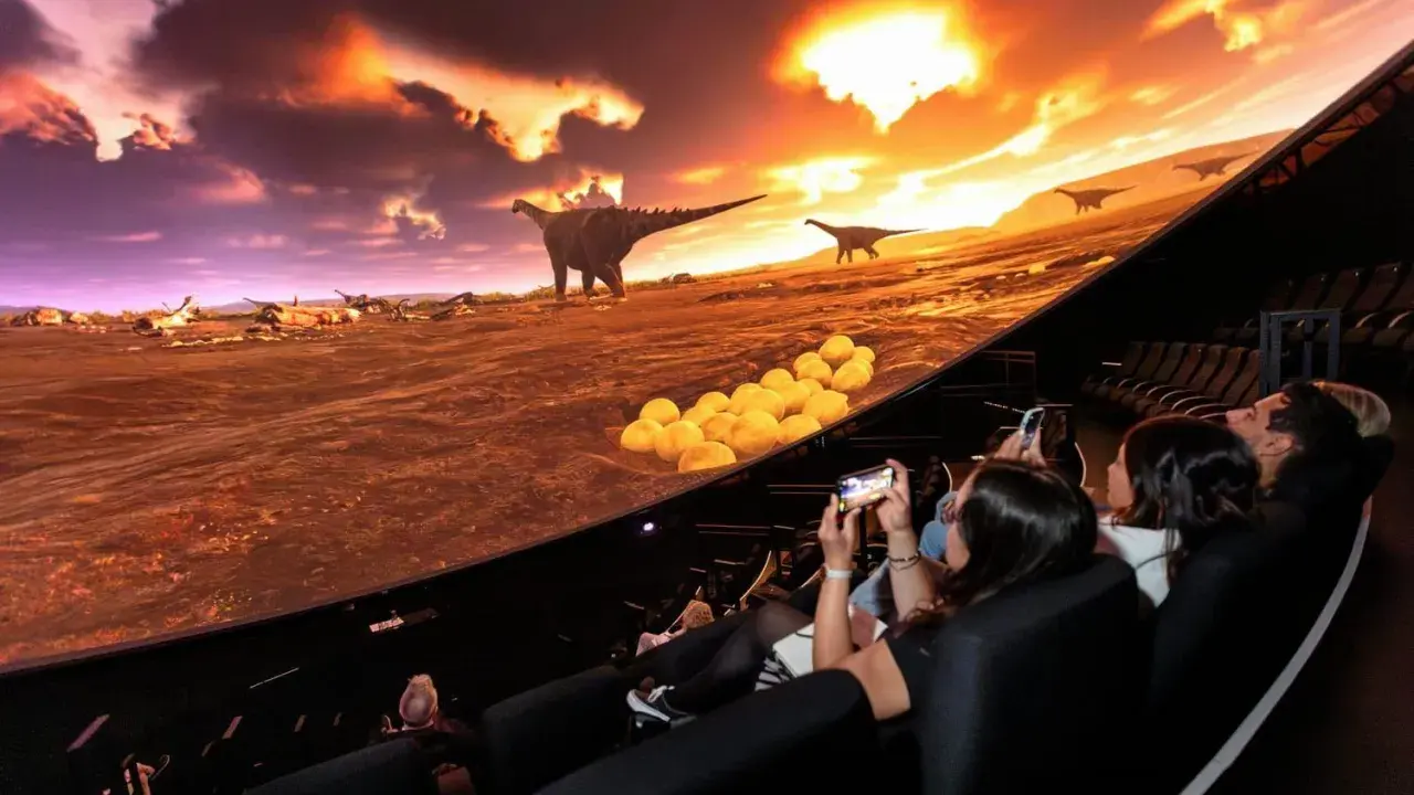 Besökare njuter av en dinosaurieupplevelse i en kupolformad salong, som en del av universum i Göteborg.