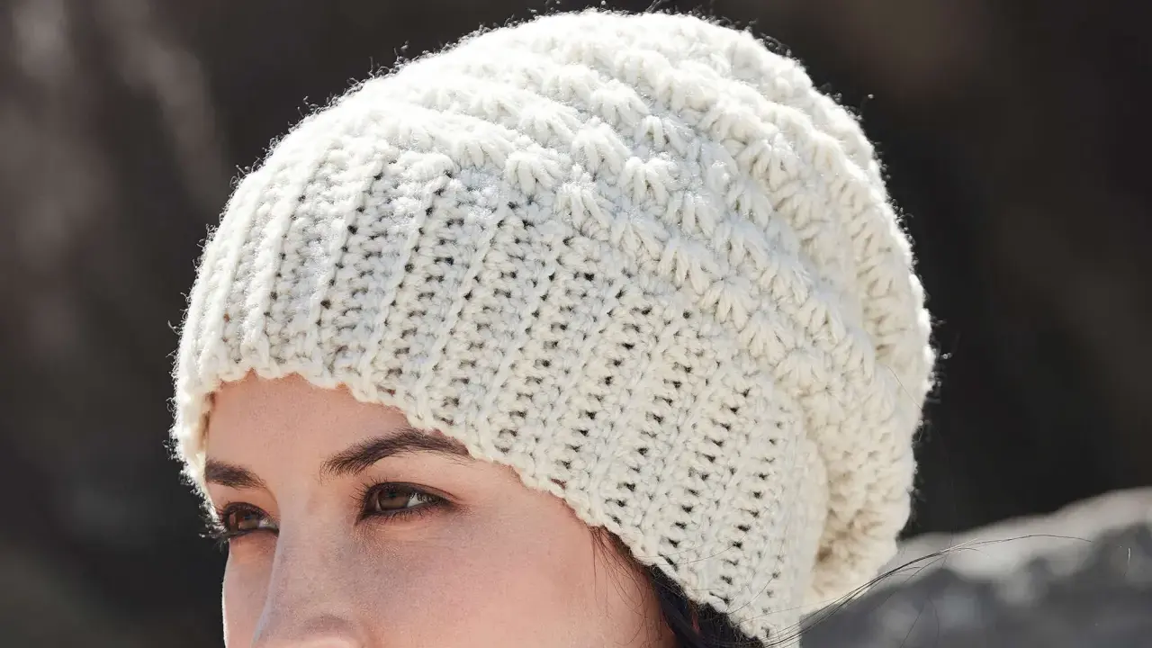 Mujer con gorro de ganchillo blanco con patrón texturizado. ¡Encuentra gorros de ganchillo patrones gratis para crear el tuyo!