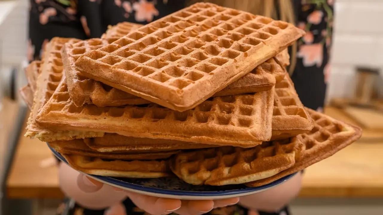 Une assiette débordante de gaufres dorées, parfaites pour une recette de gaufres croustillantes et moelleuses. Un délice à partager !