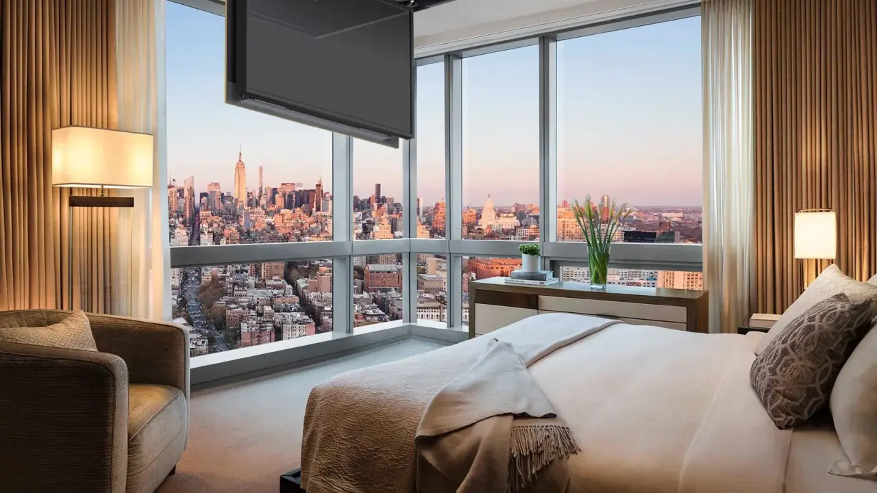 Camera da letto con vista su New York, dove una tv nascosta a soffitto scompare quando non serve, lasciando spazio al panorama.