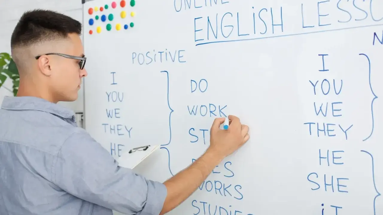 Chłopak pisze na tablicy "English Lesson". To materiał na blog język angielski o gramatyce.