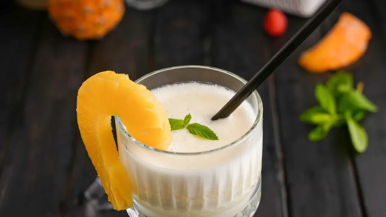 En krämig pina colada med ananasskiva och mynta, redo att avnjutas.