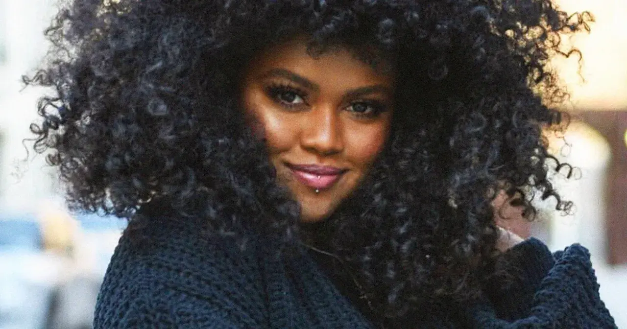 A woman with voluminous, natural curly hair, showcasing beautiful hairstyles for natural curly hair.