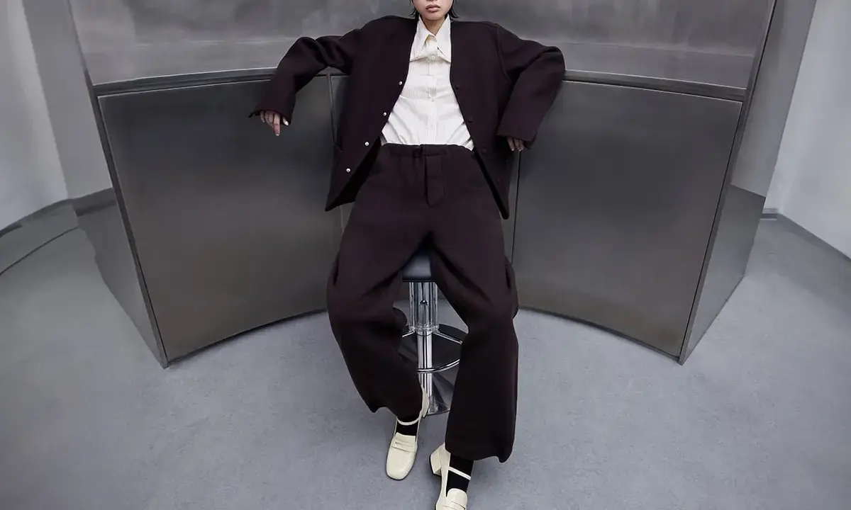 A woman in a dark suit and cream blouse wears cream loafers, showcasing what shoes are considered business casual for a woman.
