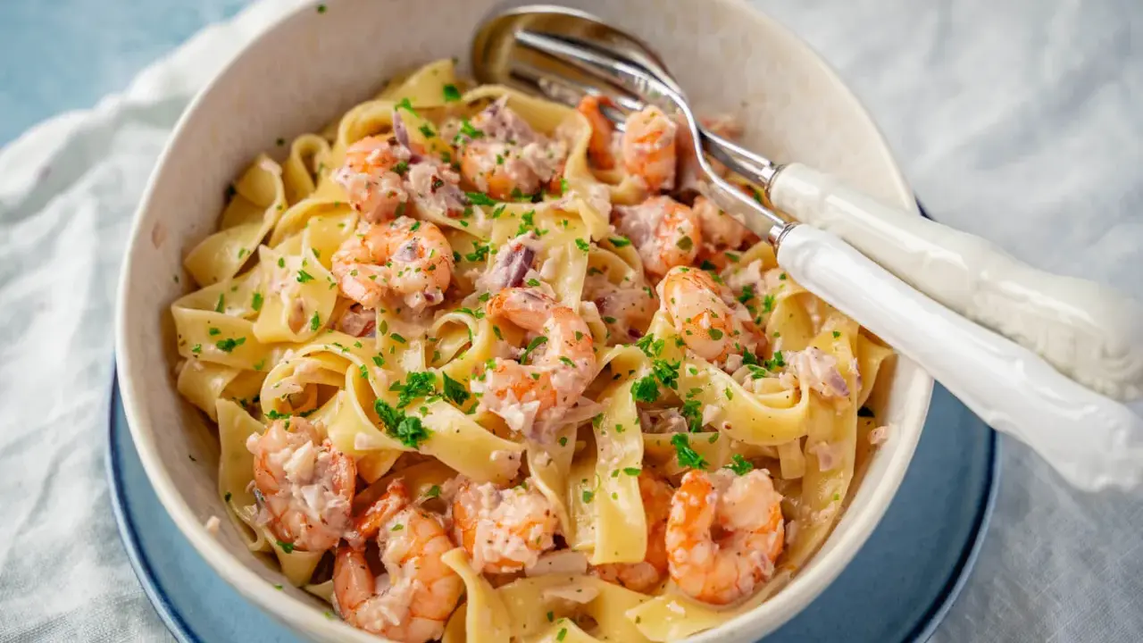 Breite Bandnudeln mit saftigen Garnelen in cremiger Sauce, garniert mit frischer Petersilie. Ein köstliches Gericht mit Spaghetti und Garnelen.