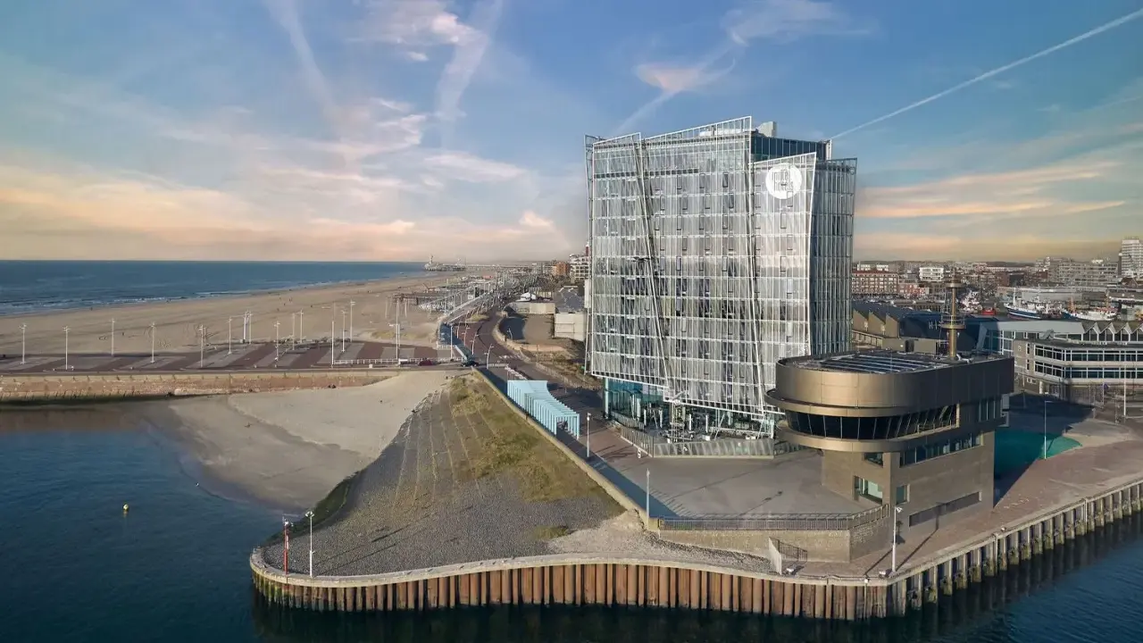 Modernes Hotel am Meer mit Glasfassade, Strand und Hafen.