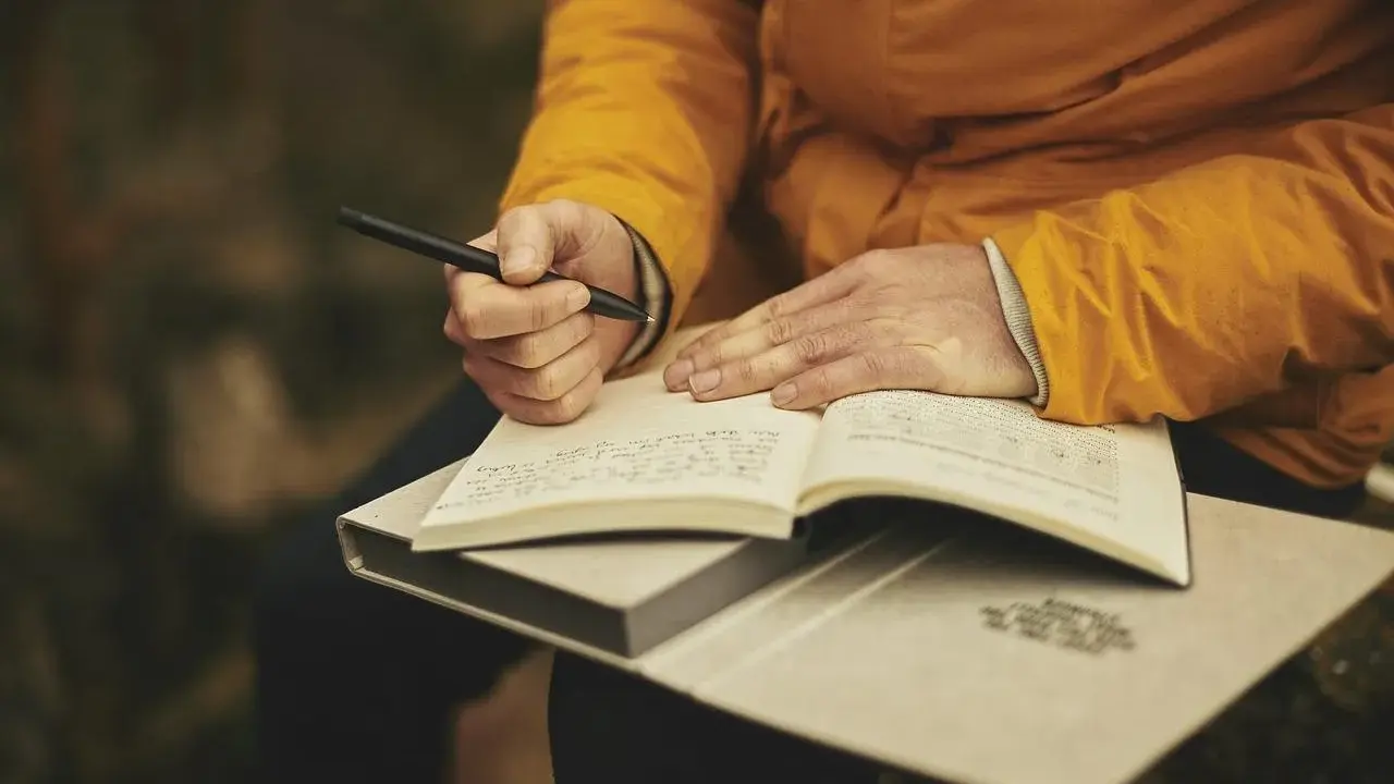 Mani che scrivono su un quaderno aperto, ispirate dalle riviste letterarie italiane.