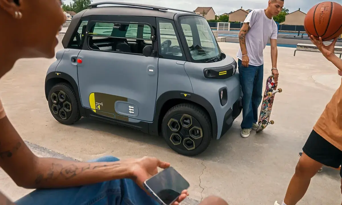 Jóvenes con patineta y balón de baloncesto cerca de un coche gris. ¡Qué ganas de tener el permiso AM que puedo conducir!