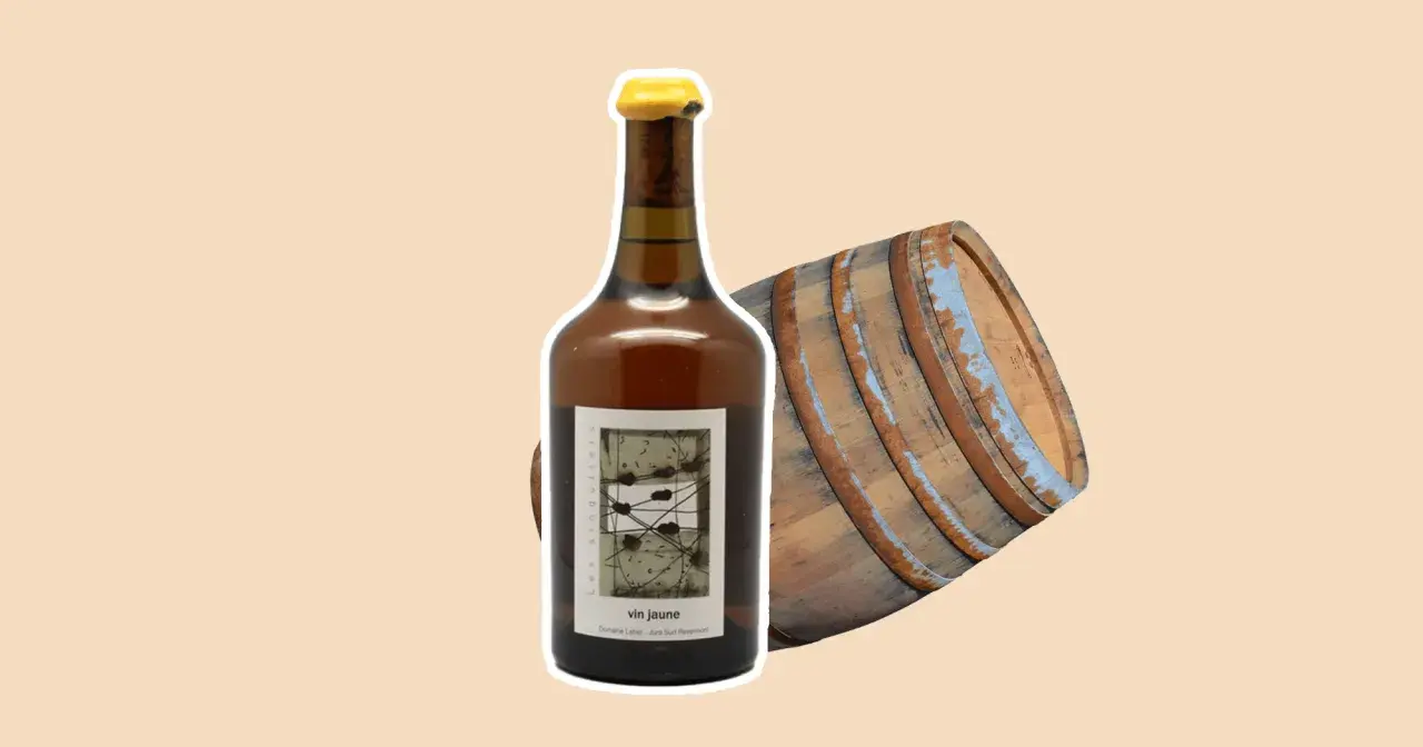 Bouteille de vin jaune à côté d'un vieux fût de chêne. Le vin jaune, une spécialité du Jura, est un vin oxydatif unique.