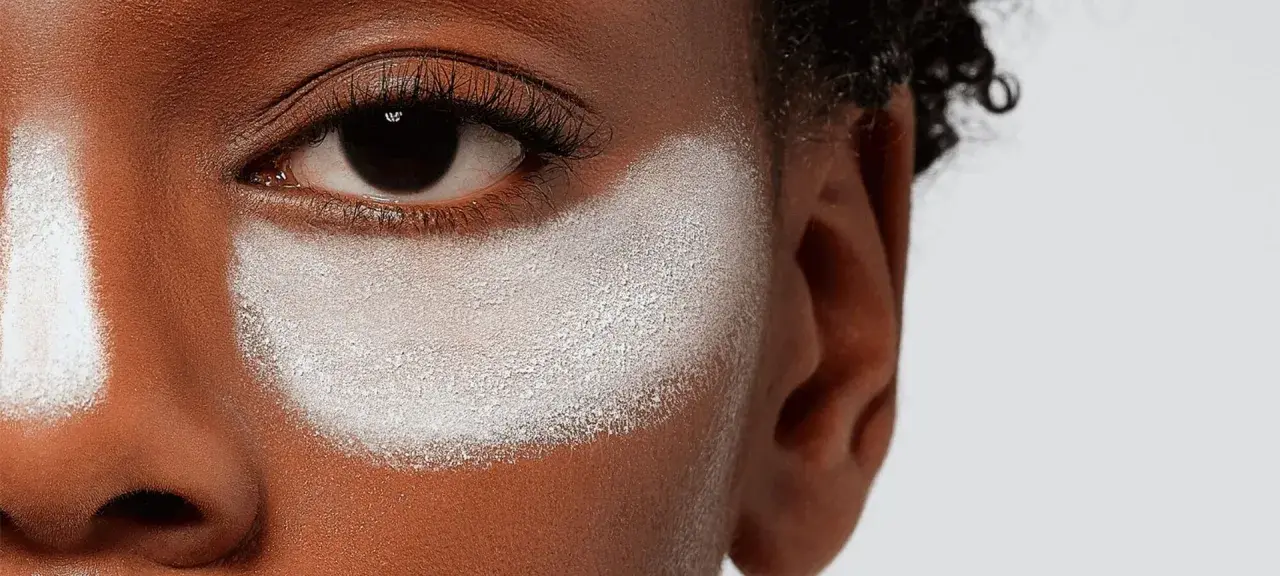 Primo strato di cipria prima del fondotinta, evidenzia la texture della pelle e la preparazione per un makeup impeccabile.