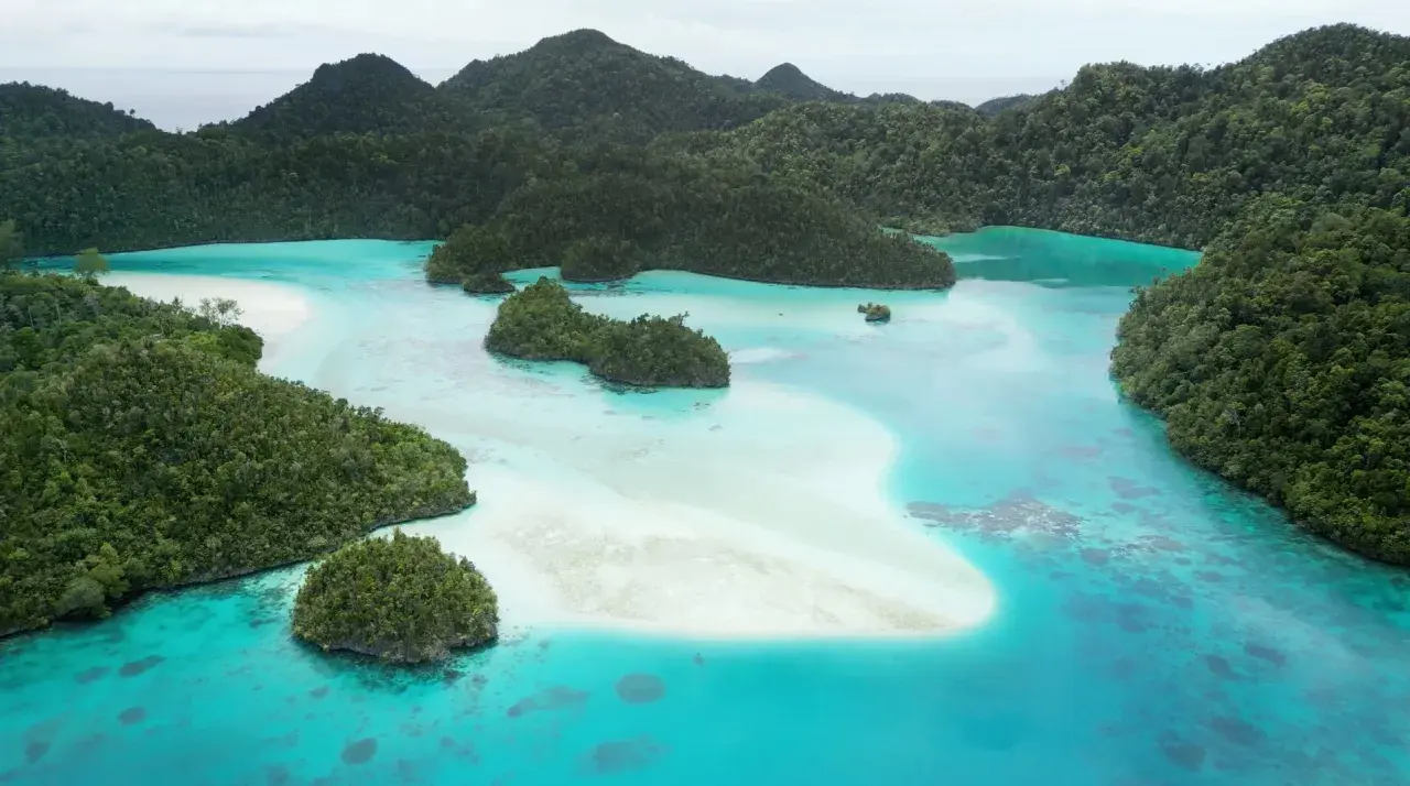 Rajskie krajobrazy Raja Ampat: turkusowe laguny, piaszczyste ławice i bujna zieleń tropikalnych wysp.
