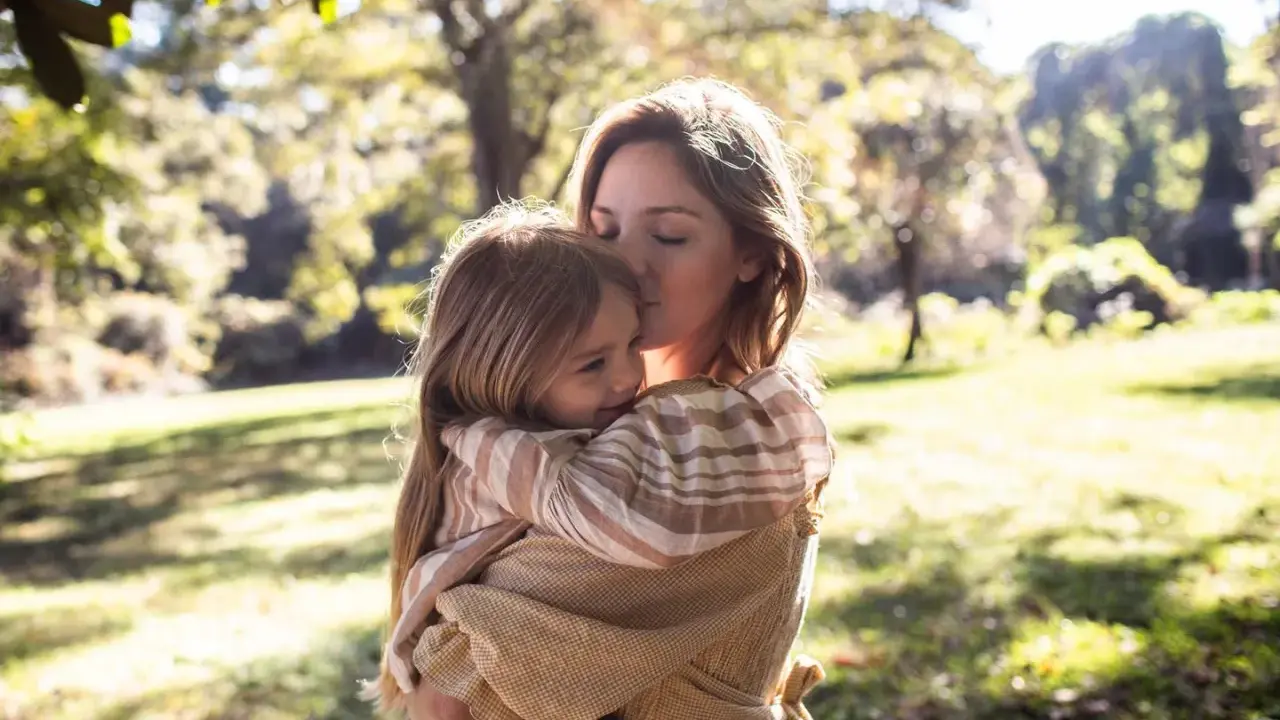 Mutter küsst ihr Kind zärtlich im Arm. Ein Moment voller Liebe, der die Essenz von gentle parenting deutsch widerspiegelt.