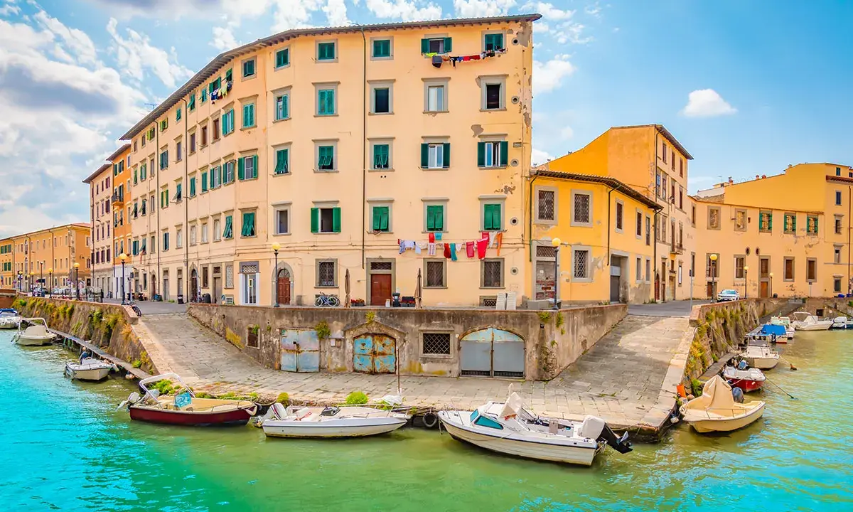 Canali di Livorno, un'idea per cosa vedere a Livorno in un giorno. Case colorate e barche sull'acqua turchese.