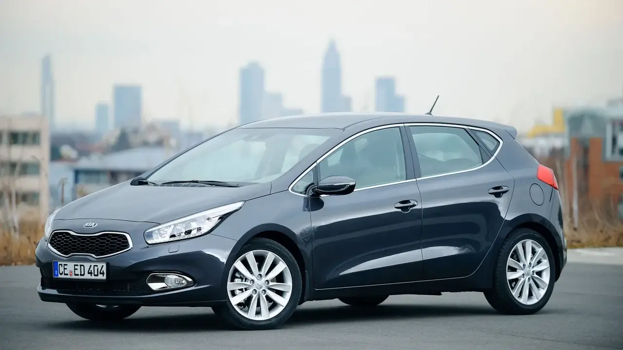 Ciemnoszary Kia Ceed 1.6 benzyna stoi na tle miejskiego krajobrazu.