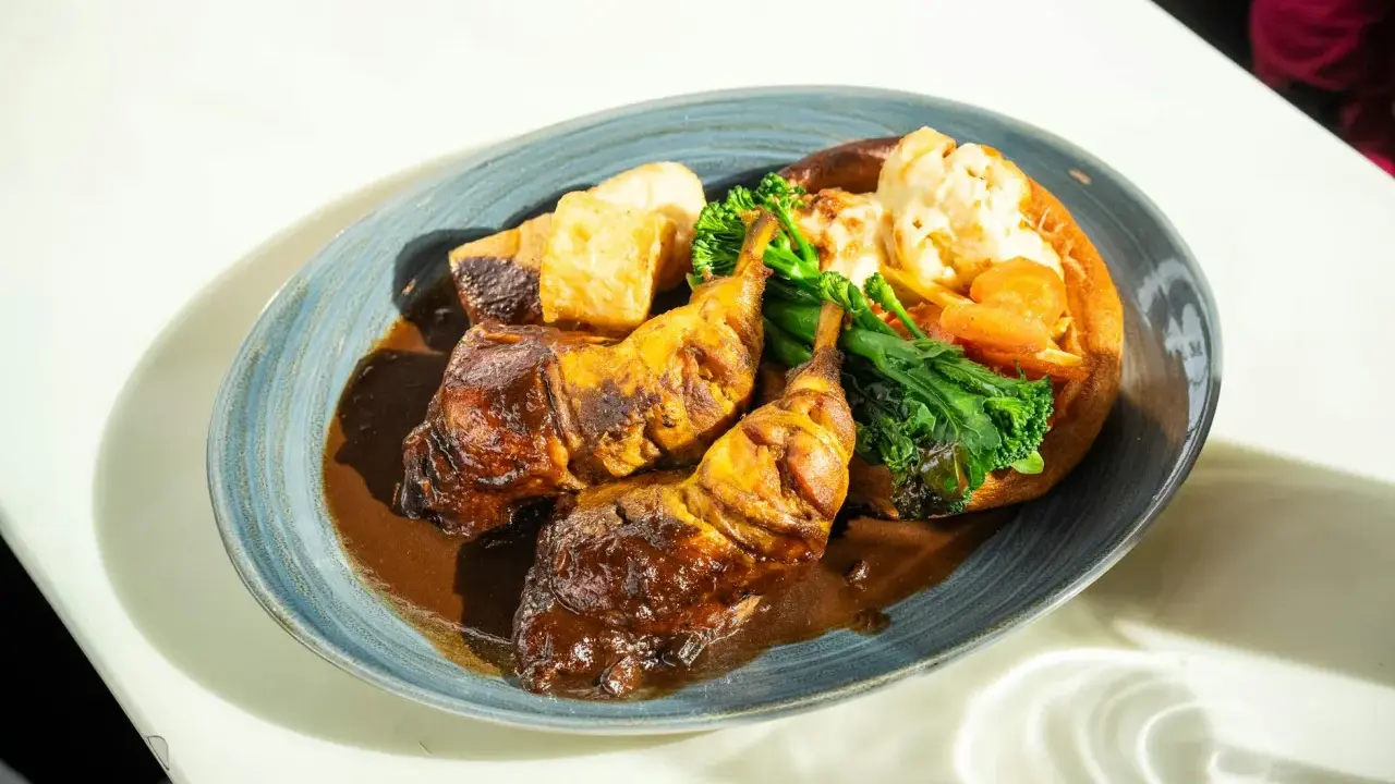 Pyszny niedzielny obiad: pieczone udka kurczaka w sosie, pieczone ziemniaki, brokuły i kalafior zapiekany w Yorkshire pudding.